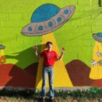 Kid posing near alien wall art