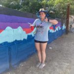 Woman posing next to wall art